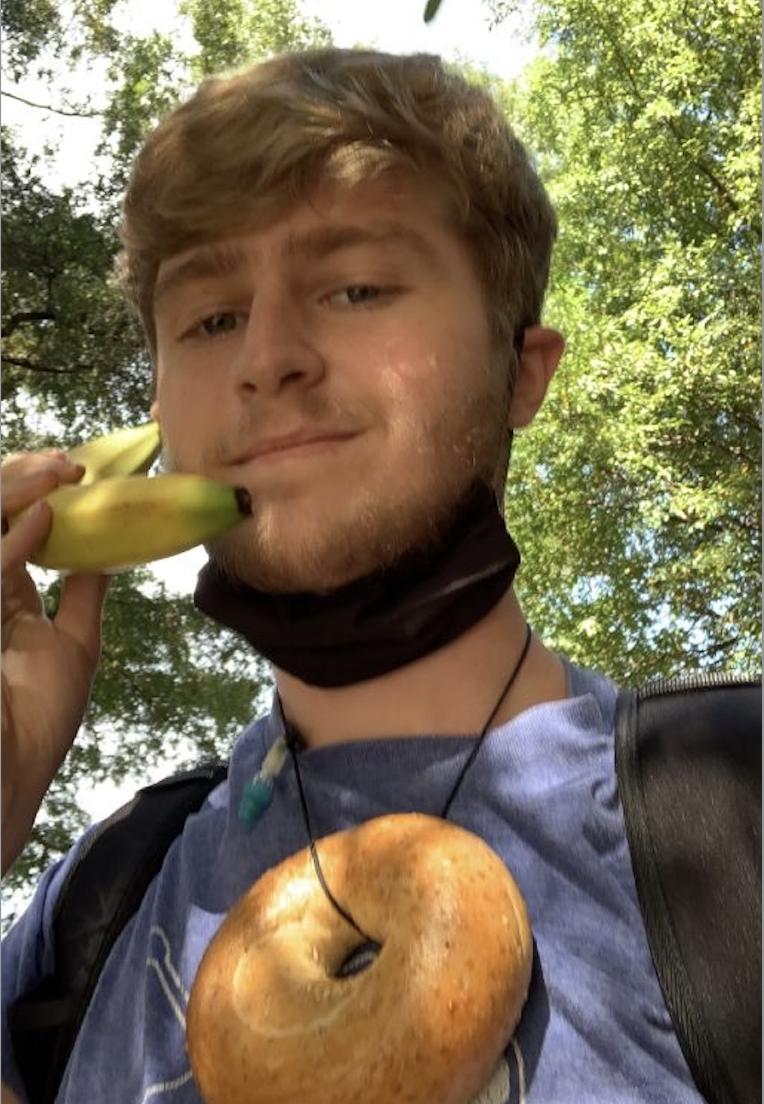 Nathan Snow wears a bagel necklace and holds a banana phone for a Sock Wars immunity.